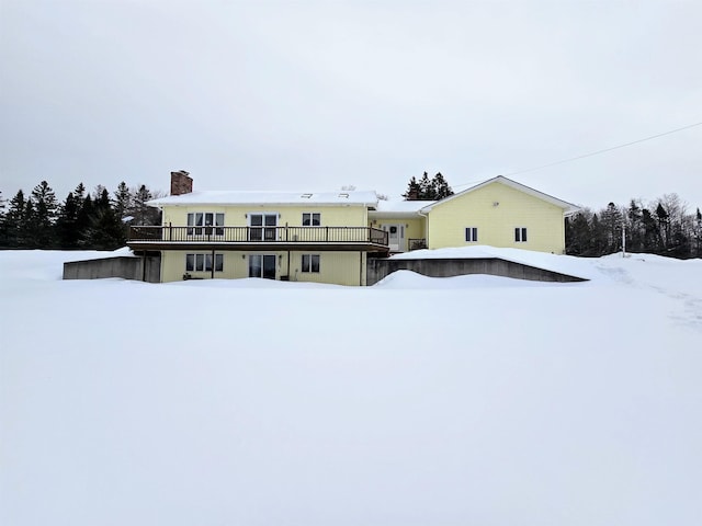 snow covered house featuring a chimney