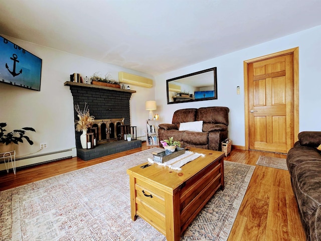 living area featuring a wall unit AC, baseboard heating, a brick fireplace, wood finished floors, and baseboards