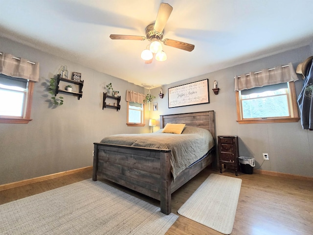 bedroom with multiple windows, wood finished floors, and baseboards