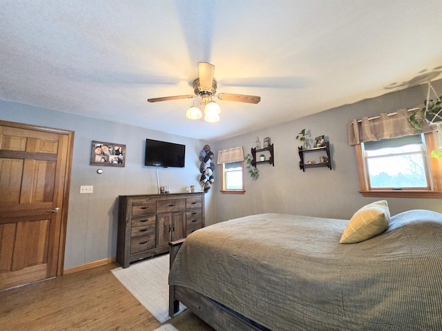 bedroom featuring a ceiling fan, baseboards, and light wood finished floors