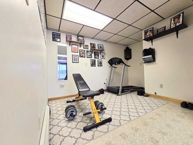 workout room featuring a baseboard heating unit, a drop ceiling, and baseboards