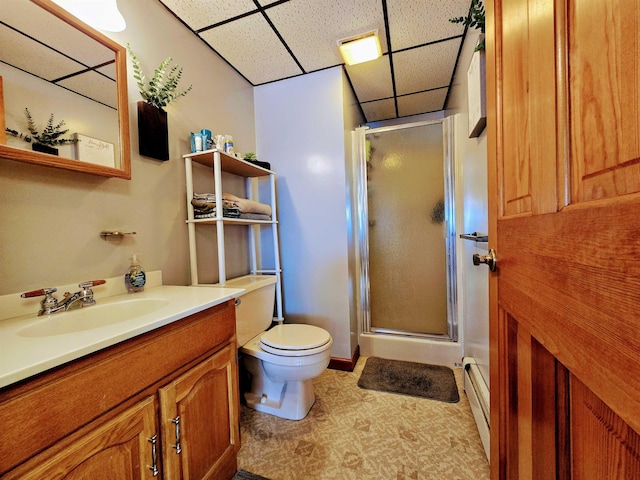 bathroom featuring toilet, vanity, a shower stall, and a paneled ceiling