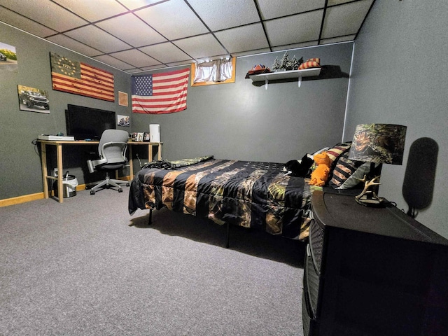 bedroom featuring a drop ceiling, carpet, and baseboards