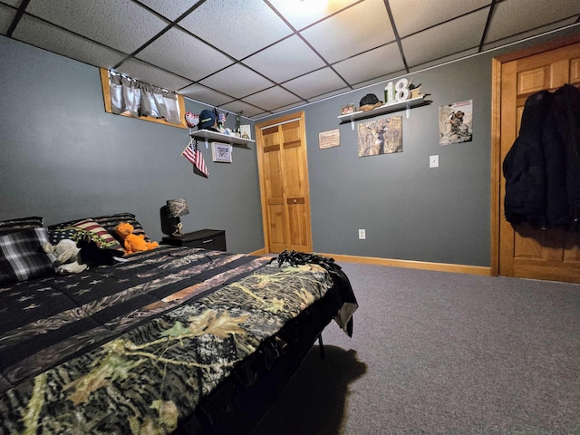 carpeted bedroom with a drop ceiling and baseboards