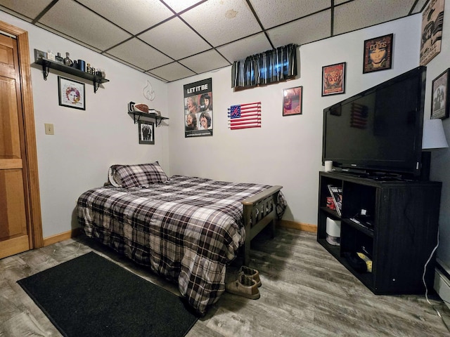 bedroom featuring a paneled ceiling, baseboards, and wood finished floors