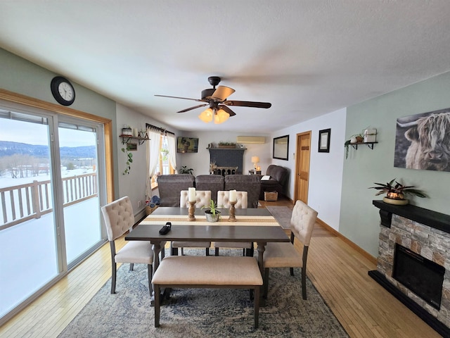 dining room featuring a wall unit AC, hardwood / wood-style flooring, and a fireplace