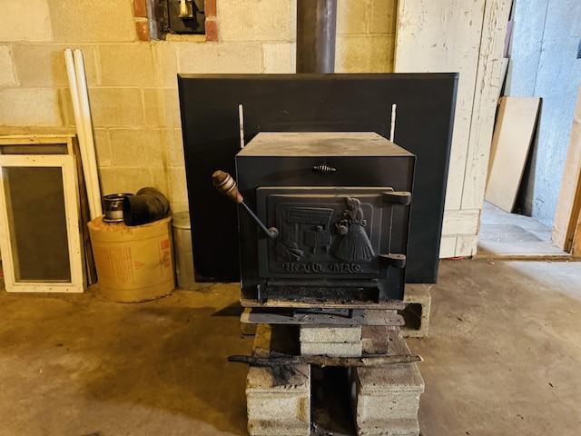 details with concrete floors, a wood stove, and concrete block wall