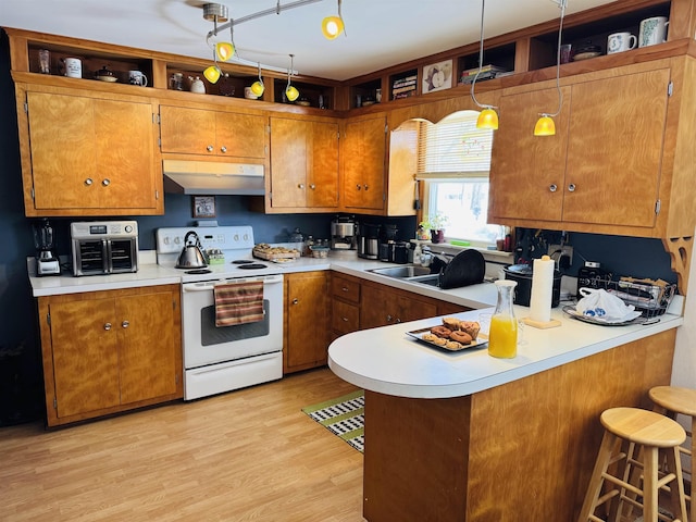 kitchen with electric range, brown cabinets, a peninsula, light countertops, and under cabinet range hood