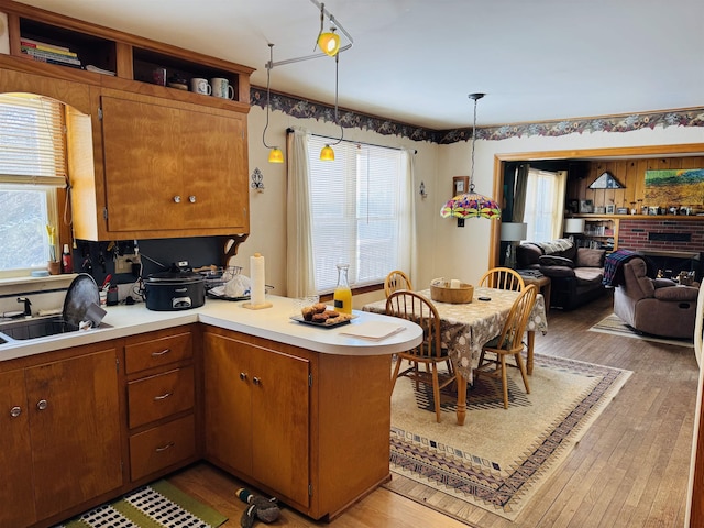 kitchen featuring light countertops, a peninsula, a sink, and light wood-style floors