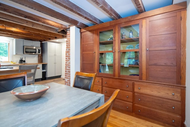 dining room with beamed ceiling and light wood finished floors