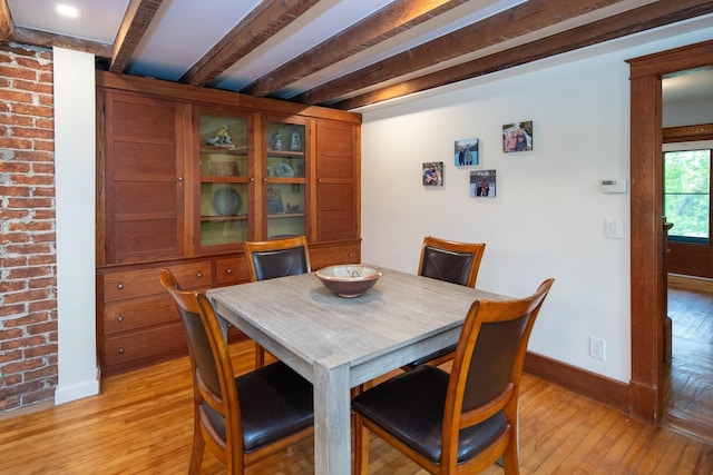 dining area with beamed ceiling, light wood-style flooring, and baseboards