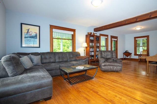 living room featuring beam ceiling, light wood-style floors, and baseboards