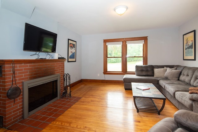 living room with a fireplace, baseboards, and wood finished floors