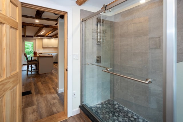 full bathroom with baseboards, beam ceiling, wood finished floors, and a shower stall