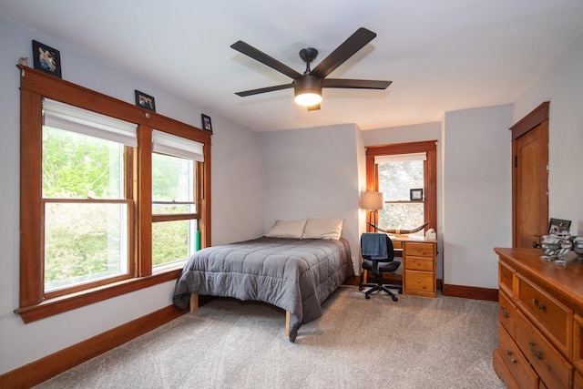 bedroom with a ceiling fan, multiple windows, light colored carpet, and baseboards