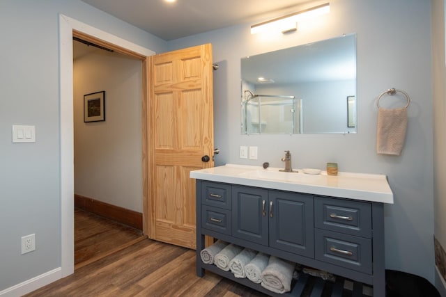 full bath with baseboards, wood finished floors, and vanity