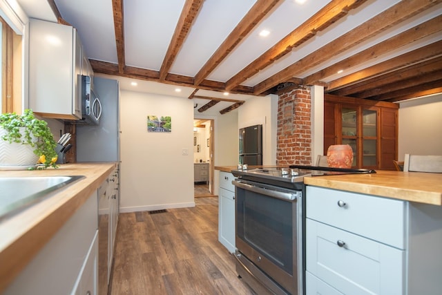 kitchen with beam ceiling, dark wood-type flooring, stainless steel appliances, white cabinets, and wooden counters