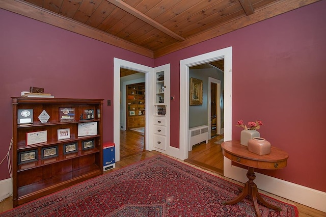 hall with built in shelves, wood finished floors, wood ceiling, baseboards, and radiator