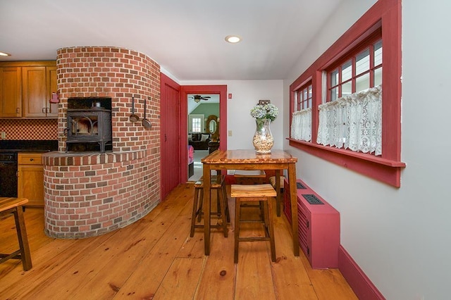 dining space with light wood-type flooring, a wood stove, baseboards, and recessed lighting