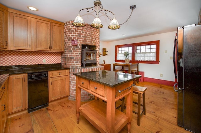 kitchen featuring brown cabinetry, decorative backsplash, freestanding refrigerator, and light wood-style floors