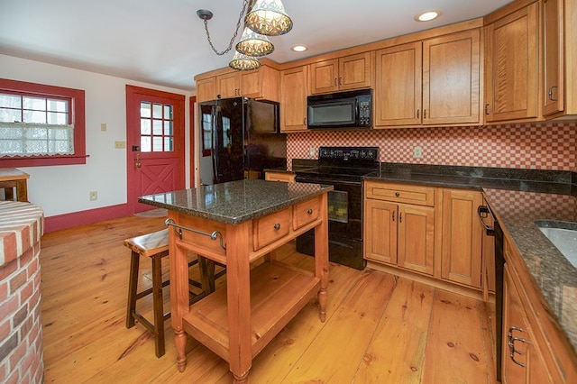 kitchen with light wood-style floors, baseboards, backsplash, and black appliances