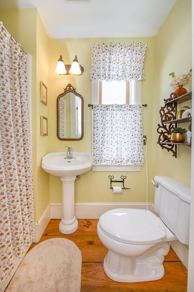 full bath with visible vents, toilet, wood finished floors, a shower with curtain, and baseboards