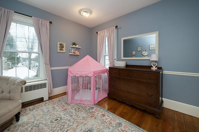 bedroom featuring hardwood / wood-style floors, radiator heating unit, and baseboards