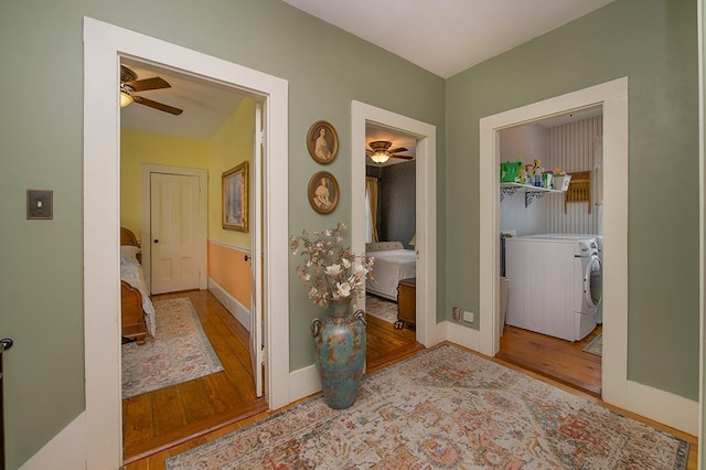 hallway featuring baseboards, washer and dryer, and wood finished floors