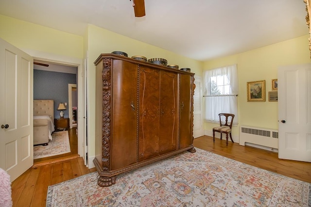 bedroom featuring wood-type flooring, ceiling fan, and radiator heating unit