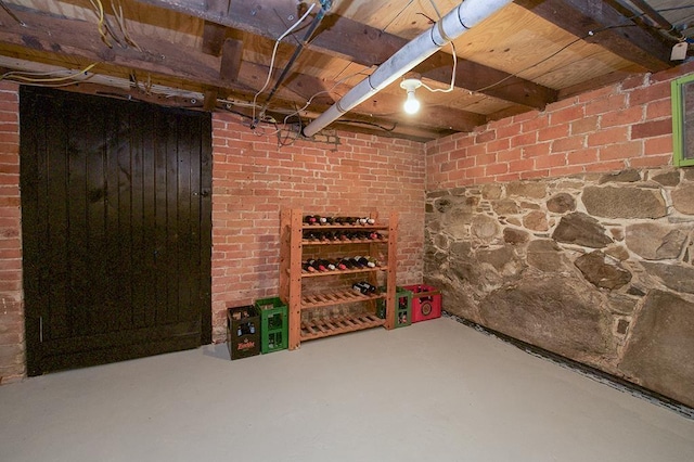 wine area featuring brick wall and concrete floors