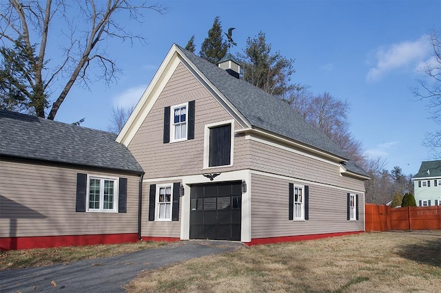 view of front of house with a front yard, roof with shingles, fence, and a chimney