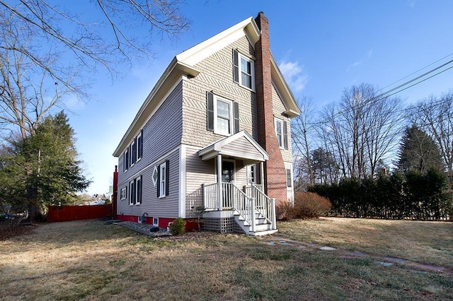 view of front of house with a chimney, fence, and a front yard