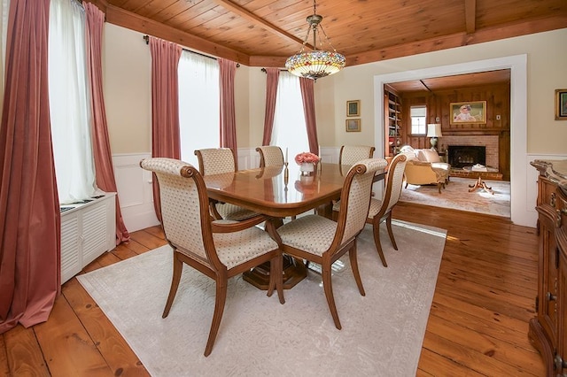 dining space featuring a wealth of natural light, a brick fireplace, wood ceiling, and light wood-style floors