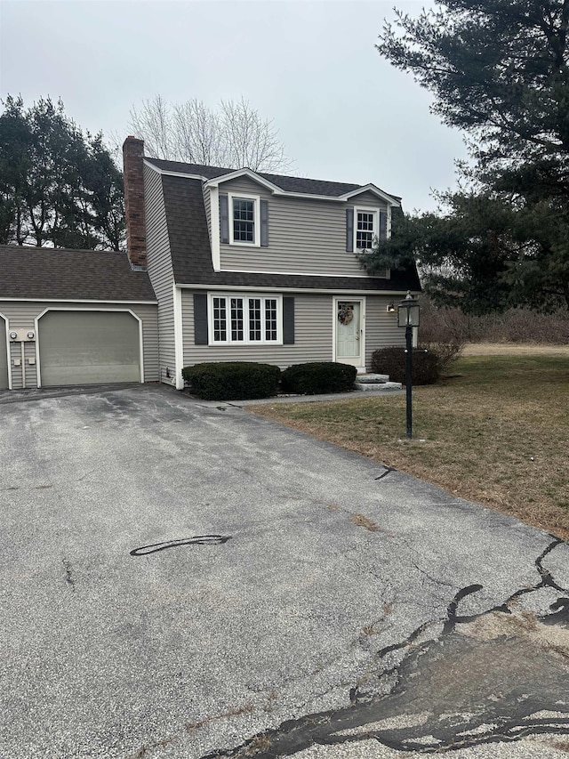 view of front of house featuring aphalt driveway, roof with shingles, a chimney, an attached garage, and a front yard