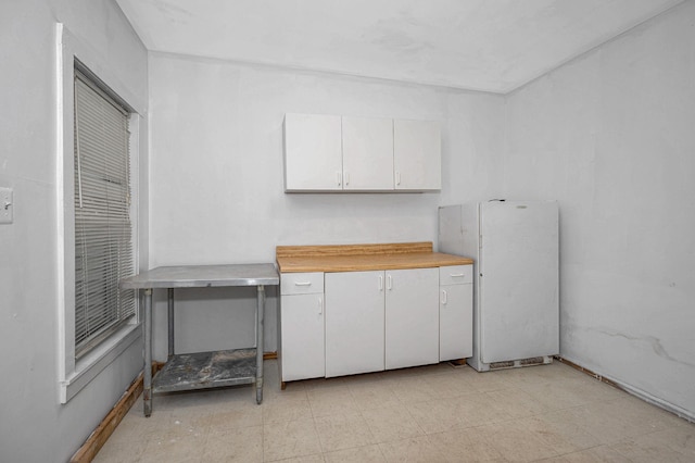 kitchen with freestanding refrigerator and white cabinets