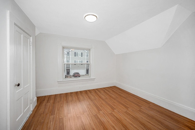 additional living space with lofted ceiling, light wood-type flooring, and baseboards