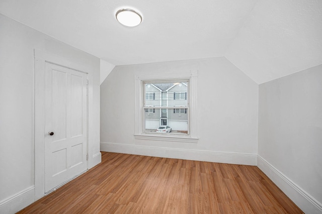 bonus room featuring lofted ceiling, light wood-type flooring, and baseboards