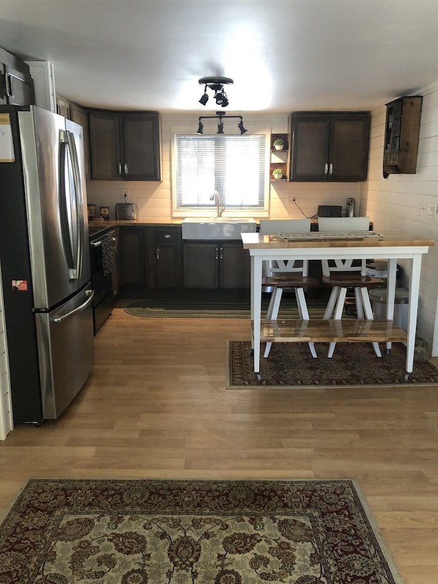 kitchen featuring light wood-type flooring, freestanding refrigerator, a sink, and electric range oven