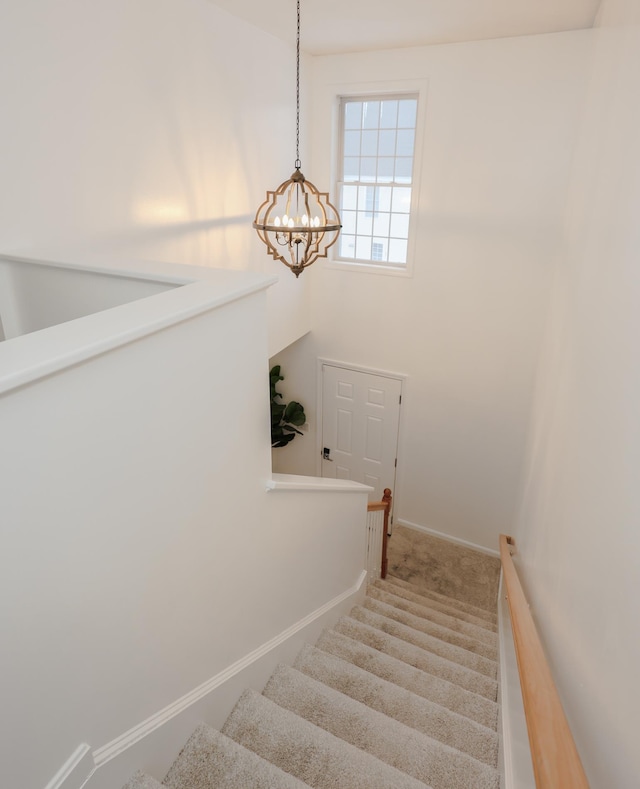 stairs featuring a notable chandelier, baseboards, and carpet flooring