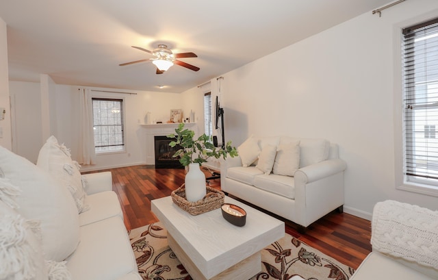 living area with a fireplace with flush hearth, ceiling fan, wood finished floors, and baseboards