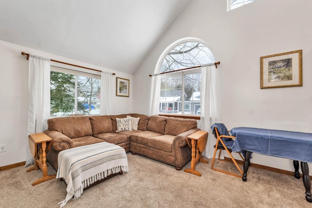 living area with light carpet, high vaulted ceiling, and baseboards