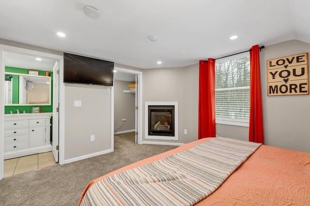 carpeted bedroom featuring a sink, a spacious closet, a glass covered fireplace, and recessed lighting