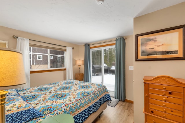 bedroom with access to outside, wood finished floors, and baseboards