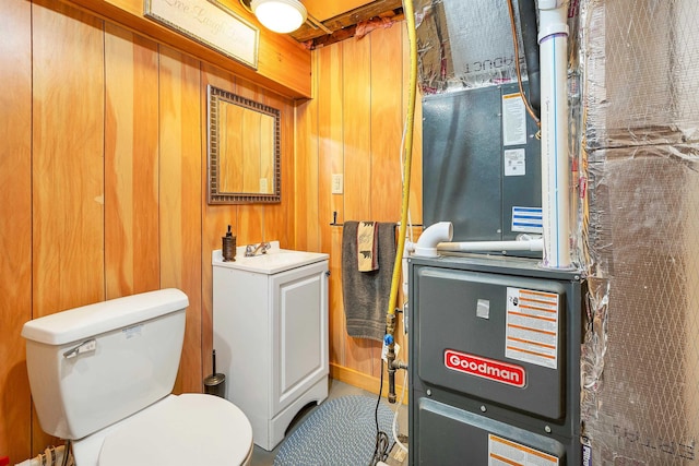 bathroom featuring heating unit, a sink, toilet, and wooden walls