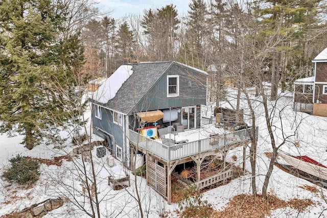 snow covered rear of property with roof with shingles