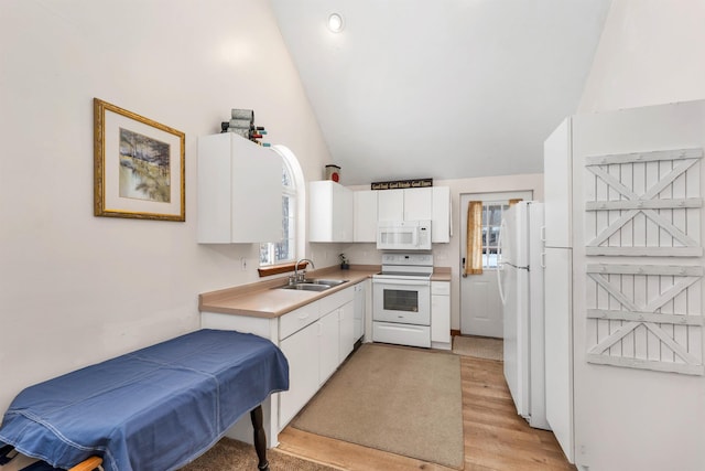 kitchen with white appliances, vaulted ceiling, white cabinets, and a sink