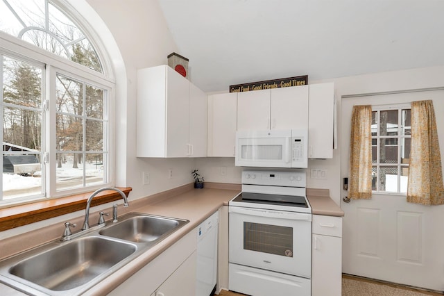 kitchen with white appliances, white cabinets, a sink, and light countertops