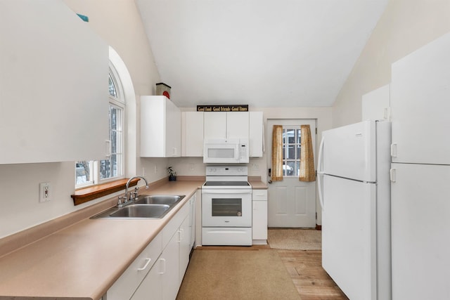 kitchen featuring lofted ceiling, white appliances, white cabinetry, and a sink