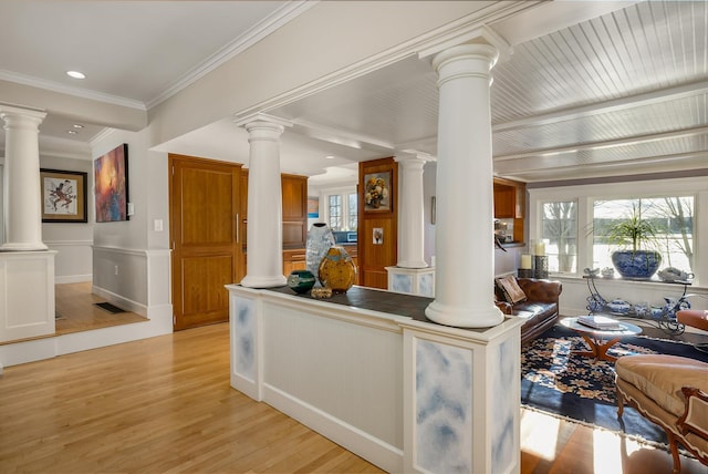 interior space with light wood-style floors, ornamental molding, and ornate columns