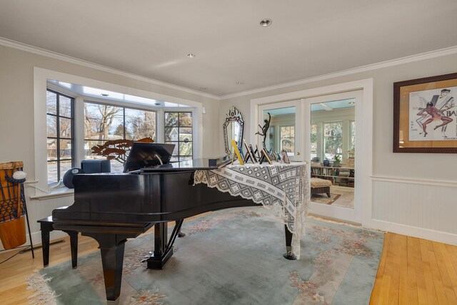 sitting room with french doors, wainscoting, crown molding, and wood finished floors